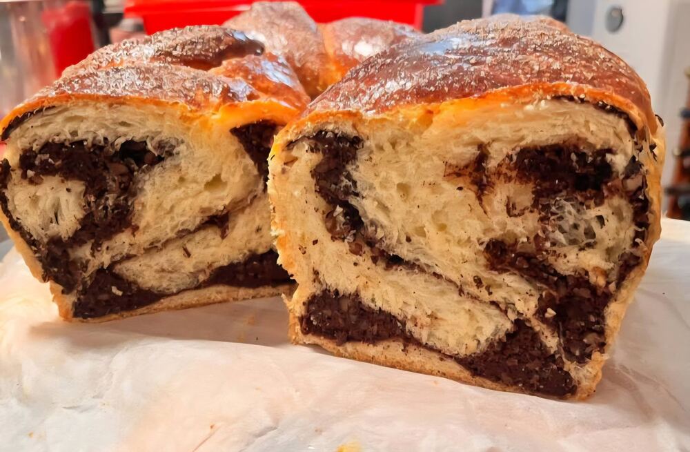 Cozonac tăiat în felii, cu umplutură de nucă și cacao vizibilă în secțiune