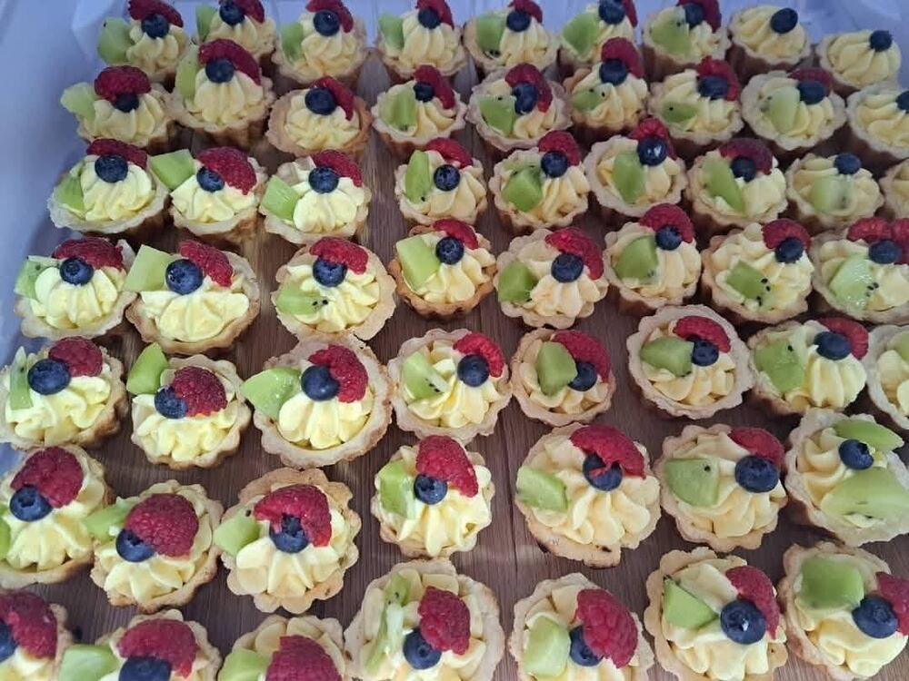 Tavă cu mini-tartelete umplute cu cremă de vanilie, decorate cu zmeură, afine și kiwi