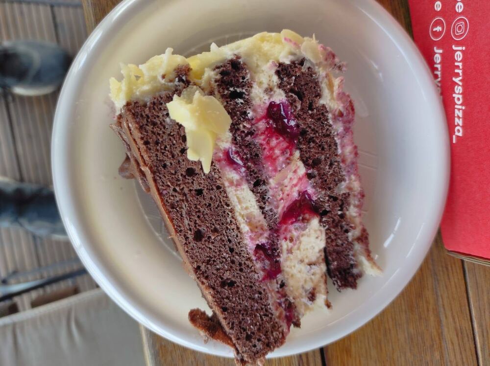 Felie de tort cu blat de cacao, cremă albă și jeleu de fructe de pădure